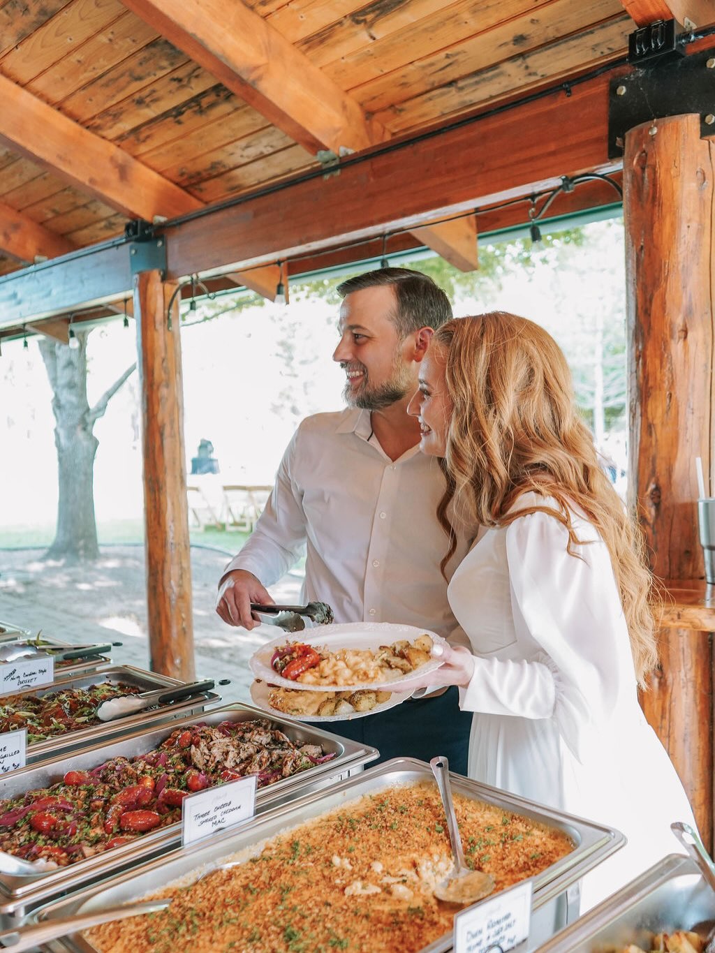 Guests serving themselves from a buffet of scratch-made dishes at an outdoor wedding