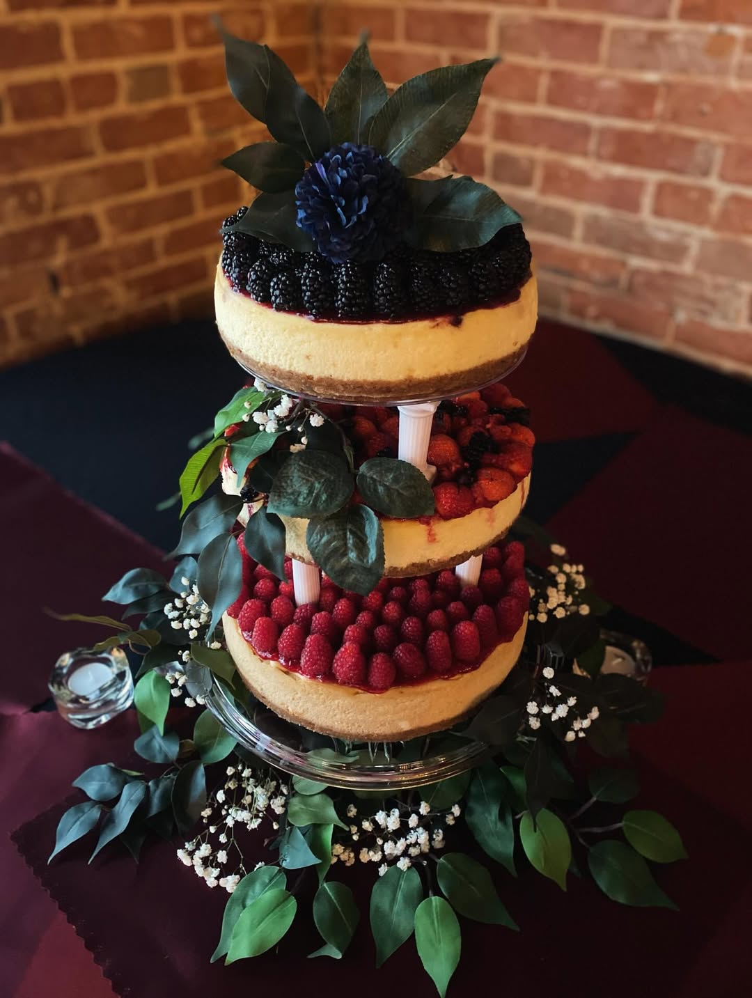 Two-tier naked cake topped with blackberries, raspberries and greenery