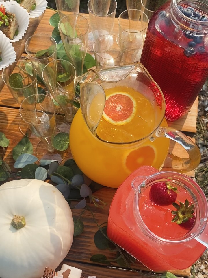 Glass drink dispensers with citrus punch and berry lemonade on a wooden bar